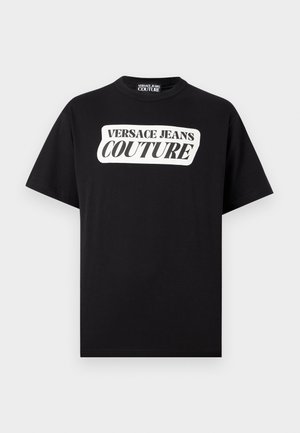 Fekete rövid ujjú póló fehér téglalap alakú logóval, középen a mellkason, amelyen a "VERSACE JEANS COUTURE" felirat olvasható.