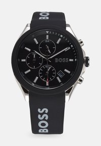 Black silicone strap watch with a textured black dial, silver-tone accents, three subdials, and a date display. Features "BOSS" branding.