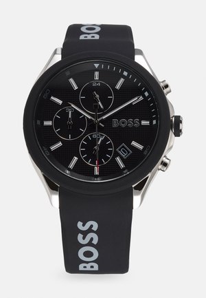 Schwarze Silikonarmbanduhr mit strukturiertem schwarzem Ziffernblatt, Akzenten in Silberfarbe, drei Unterzifferblättern und einem Datumsdisplay. Mit 'BOSS'-Logo.