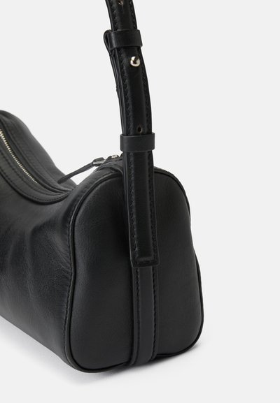 Bolsa de mão de couro preto com uma textura lisa, apresentando um fecho com zíper, uma forma estruturada e uma alça de ombro ajustável e fina.