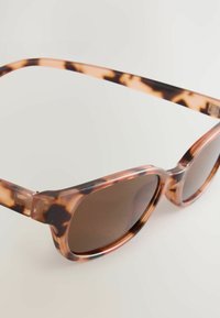 Gafas de sol con patrón de carey, con un marco grueso, lentes redondeados y cristal tintado marrón. Hechas de plástico con una textura suave.
