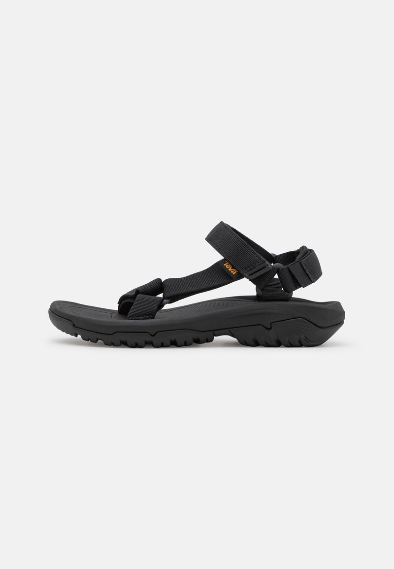 Black sandals with adjustable straps, textured rubber sole, and a cushioned footbed. Features a rugged outsole for traction. Lightweight design.