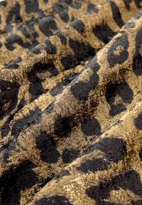 Gold and black leopard print fabric with a soft, textured surface; features a shiny finish and distinct patterns of spots and swirls.