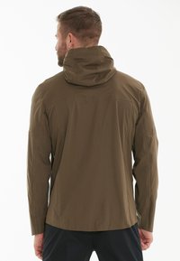 Veste imperméable vert olive avec capuche, manches longues et texture lisse. Comprend des poches latérales zippées et une coupe décontractée.