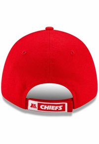 Sarkans beisbola cepure ar plakanu malu, ar baltu "CHIEFS" logo uz baltas plāksnītes aizmugurē, izgatavota no teksturēta auduma.