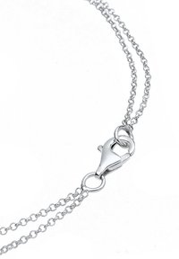 Collier à double chaîne en argent avec fermoir homard sur fond blanc.