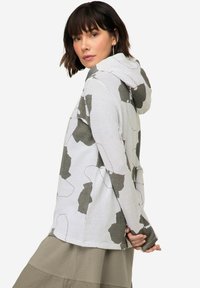 Hoodie gemaakt van textuurstof, wit met grote beige en olijfgroene abstracte patronen. Met lange mouwen en een relaxte pasvorm.