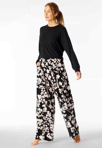 Black long-sleeve top paired with loose-fitting pants featuring a white floral pattern on a black background. The pants have side pockets.