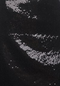 Gros plan d'un tissu noir couvert de paillettes noires et argentées brillantes éparpillées créant des motifs abstraits.