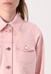Pink denim jacket featuring a collared neckline, silver hardware buttons, a chest pocket, and a speckled texture with colorful flecks.