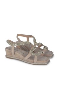 Sandali con tacco a cuneo beige in finitura scamosciata testurizzata, con dettagli metallici decorativi in un design a forma di serpente e una suola scintillante.
