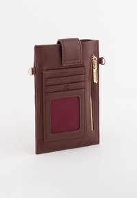 Brun læder kortholder med en lynlåslomme, flere kortslots og en maroon stofdetalje. Har guldhardware og en sikker lukning.