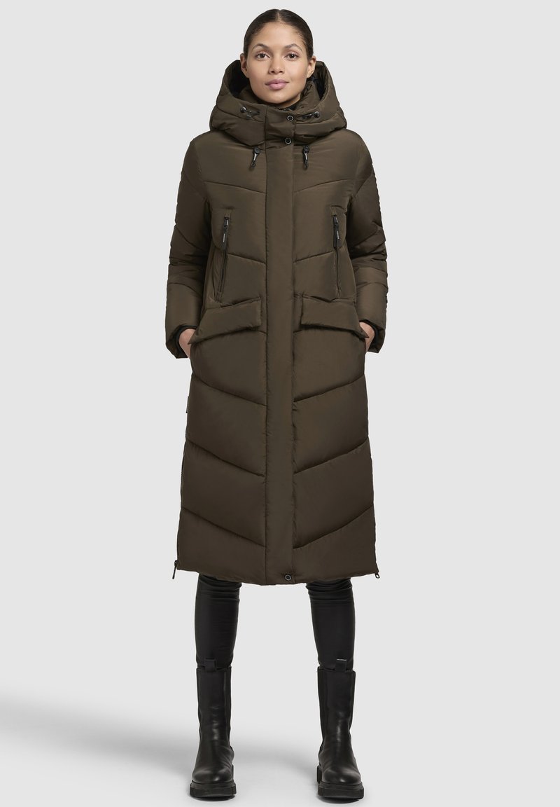 Cappotto imbottito lungo color verde oliva con cappuccio, zip frontale e cuciture diagonali. Presenta due tasche laterali e stringhe regolabili al colletto.