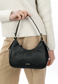 Black leather handbag with a textured surface, rounded shape, gold hardware accents, and a short strap. Zippered closure at the top.