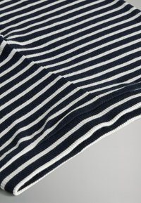 Tessuto a strisce blu navy e bianche con una texture a coste, caratterizzato da strisce alternate sottili e larghe, piegato lungo il bordo.