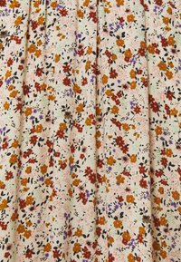 Tela floral con fondo crema y pequeñas flores en naranja, púrpura y negro, creando un diseño texturizado y con patrón.