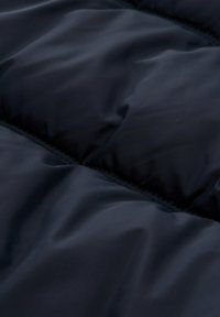 Jūras spēku puffa audums ar gludu tekstūru, ar kvadrātveida šuvēm un redzamām šuvēm. Mīksts un viegls ar ūdens atgrūdošu apdari.