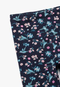 Leggings navy avec un motif floral et d'oiseaux en rose et turquoise. Tissu doux et extensible avec une coupe ajustée et une taille élastique.
