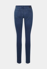 Jeans justos de cor azul escuro com cinco bolsos, feitos de tecido de denim. Apresentam uma textura suave e um design de perna reta.