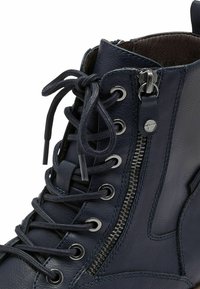 Botine din piele albastră marine, cu șireturi în față, ochiuri metalice, fermoar lateral și cusături contrastante pentru un plus de detaliu stilistic.