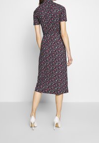 Blommig midi-klänning i marinblått tyg, med korta ärmar, figursydd midja och en svävande kjol. Utsmyckad med små multikolorade blomster.