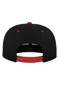 Sort snapback-cap med røde accenter. Bagsiden har et plastjusterbart bånd og ventilationshuller. Stoffet har en glat tekstur.