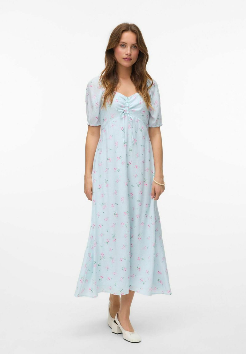 Robe maxi florale bleu clair avec des manches courtes bouffantes, détail de corsage froncé et délicates fleurs roses. Tissu lisse, silhouette fluide.