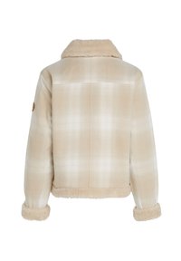 Veste à carreaux beige avec col et poignets en peau lainée, vue arrière visible, et écusson sur la manche gauche.