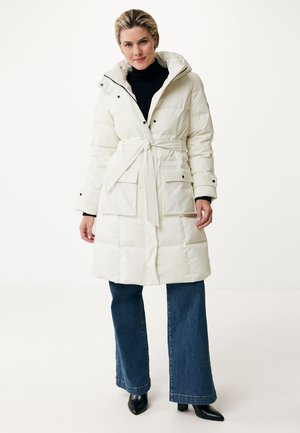 Witte pufferjas met een ceintuur, ritskap, drukknoopversiering en voorzakken. Gecombineerd met donkerblauwe flared jeans en zwarte hakken.