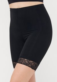 Black high-waisted shorts made of smooth fabric, featuring a lace trim at the hem, providing a contrasting texture and detail.