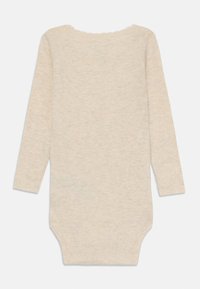 Langermet body laget av lette beige ribber, med en bølget halslinning og trykknapper nederst.