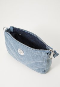Denim torbica v svetlo modri barvi, s kviltano teksturo, z zadrgo in srebrnimi dodatki. Notranjost obložena z vzorcem logotipa.