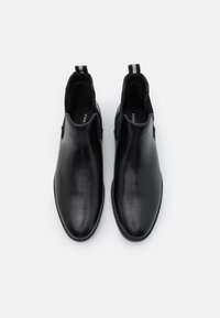 Botas de tobillo de cuero negro con un acabado suave, paneles laterales elásticos y una lengüeta. Diseño de puntera redondeada y suela plana.