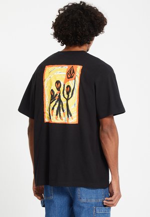 T-shirt in cotone nero con un design astratto colorato sul retro, con accenti arancioni e gialli che evidenziano figure stilizzate.