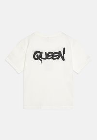 Bílá bavlněná tričko s krátkým rukávem, na zadní straně s černým sprejovým nápisem "QUEEN" a volným střihem. Hladká textura.