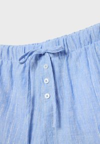Ceinture de pantalon en lin bleu clair avec élastique, trois boutons blancs et un cordon de tissu noué.