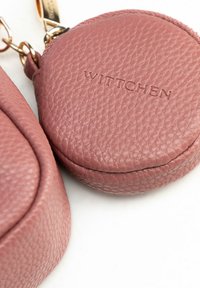 Portafoglio rotondo in pelle rosa polverosa con superficie testurizzata; logo "WITTCHEN" in rilievo; accessori in metallo dorato per il fissaggio.