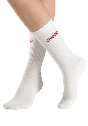 White crew socks made of cotton with ribbed texture, featuring red "CPN" text on the cuff. Mid-calf length with reinforced toe and heel.
