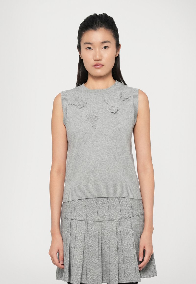 Maglione senza maniche grigio con applicazioni floreali testurizzate sul davanti, scollo e orlo a coste, abbinato a una gonna grigia plissettata.