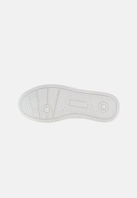 Suela de zapatilla blanca con un patrón texturizado que presenta elementos hexagonales y en zigzag. Bordes suaves y detalle de logotipo en relieve.