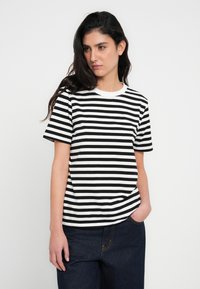 Melnās un baltās svītrainās T-krekls ar apaļu kakla izgriezumu un īsām piedurknēm, izgatavots no kokvilnas auduma, ar vaļīgu piegriezumu un gludu tekstūru.