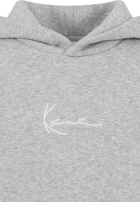 Felpa grigia con una texture morbida, caratterizzata da un logo ricamato bianco sul petto e un cappuccio con cordini. Design semplice e informale.