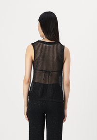 Musthave mustrisestega mustriga ja lahtise mustrigaaniga mustraidi top, millel on ümar kaelus ja vöökoht, näidates kihilist selga.