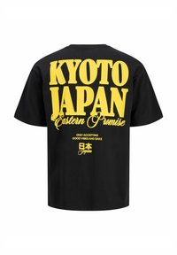 Sort bomuld t-shirt med gul tekst på bagsiden: "KYOTO JAPAN Eastern Promise" og yderligere sætninger. Rund hals og korte ærmer.