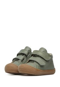Scarpe verdi in pelle con due cinturini in velcro, punta rotonda e suola in gomma marrone con texture. Presentano cuciture sottili e dettagli con logo.