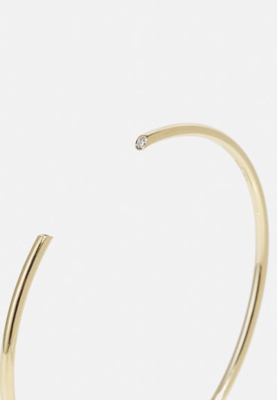 Cercei de aur cu un design elegant, curbat și un mic gemstone încorporat la vârf, evidențiind o suprafață netedă și lustruită.