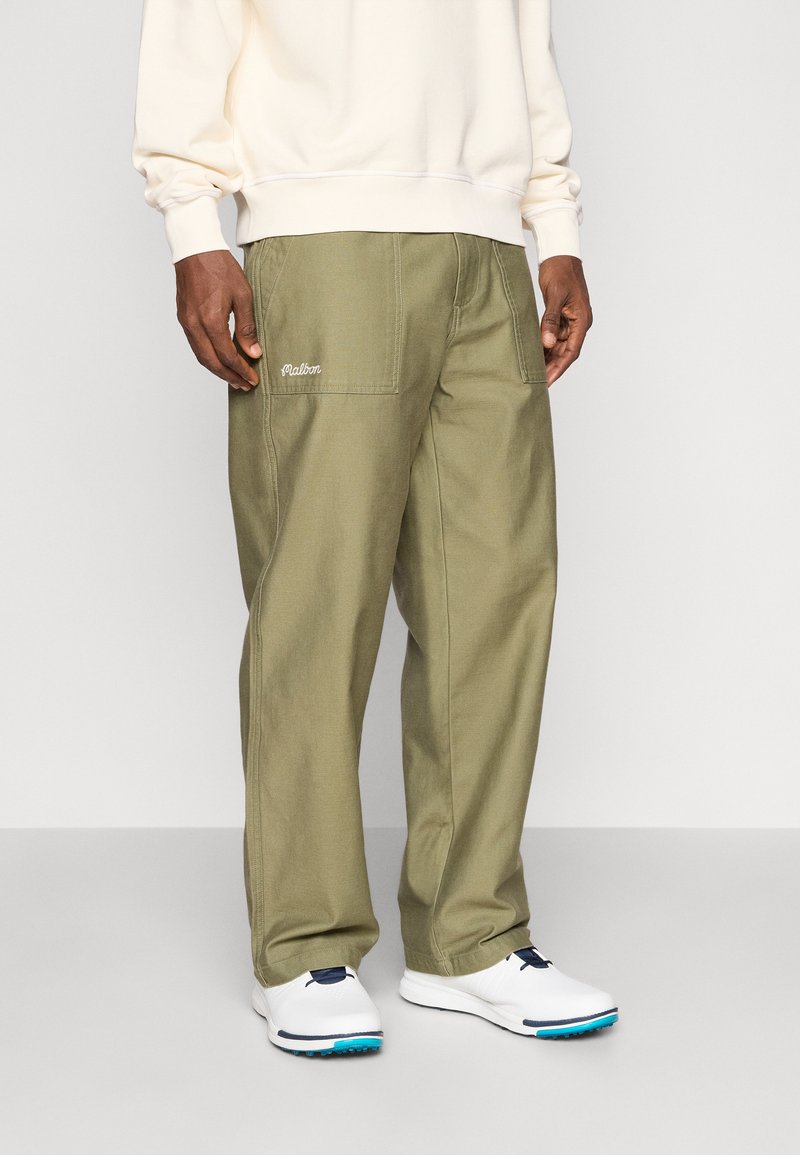 Pantaloni cargo de culoare verde măslin, cu multiple buzunare și un logo brodat alb. Asortați cu pantofi albi cu un accent albastru.