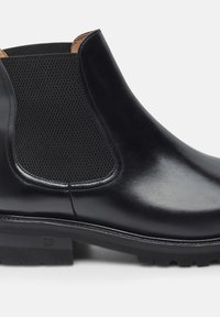 Stivale Chelsea in pelle nera con pannelli laterali in elastico texturizzato, finitura liscia e suola in gomma resistente. Dettagli cuciti sulla parte superiore.