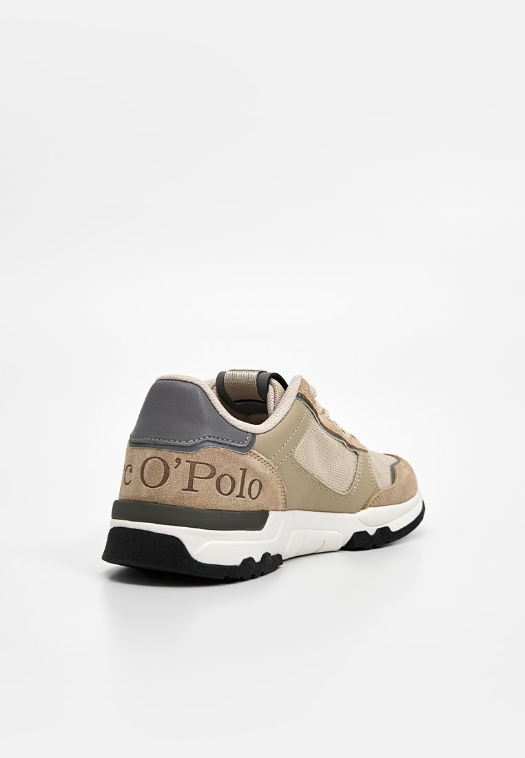 Beige und graue Sneaker aus einer Mischung von Wildleder und Mesh-Materialien, mit einem gepolsterten Kragen und einer schwarzen Gummisohle mit emblemiertem Logo-Detail.