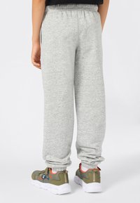 Grijze sweatpants met een elastische tailleband en aansluitende benen, gecombineerd met groene sneakers met oranje accenten en een mesh ontwerp.